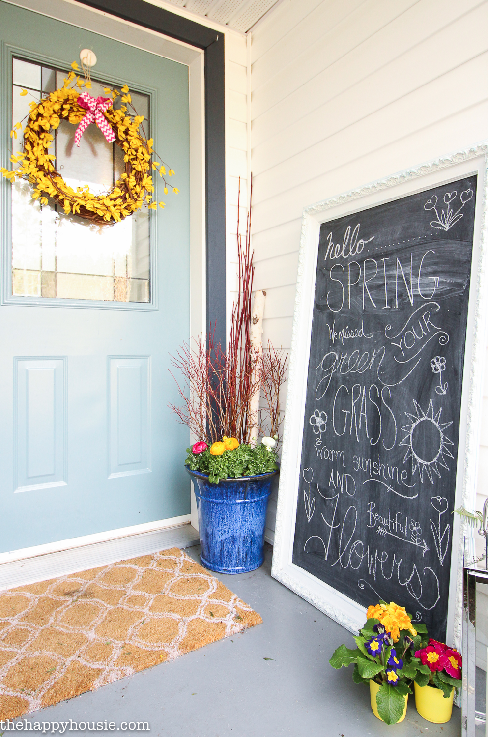 A chalkboard is on the porch with spring words and sayings on it.