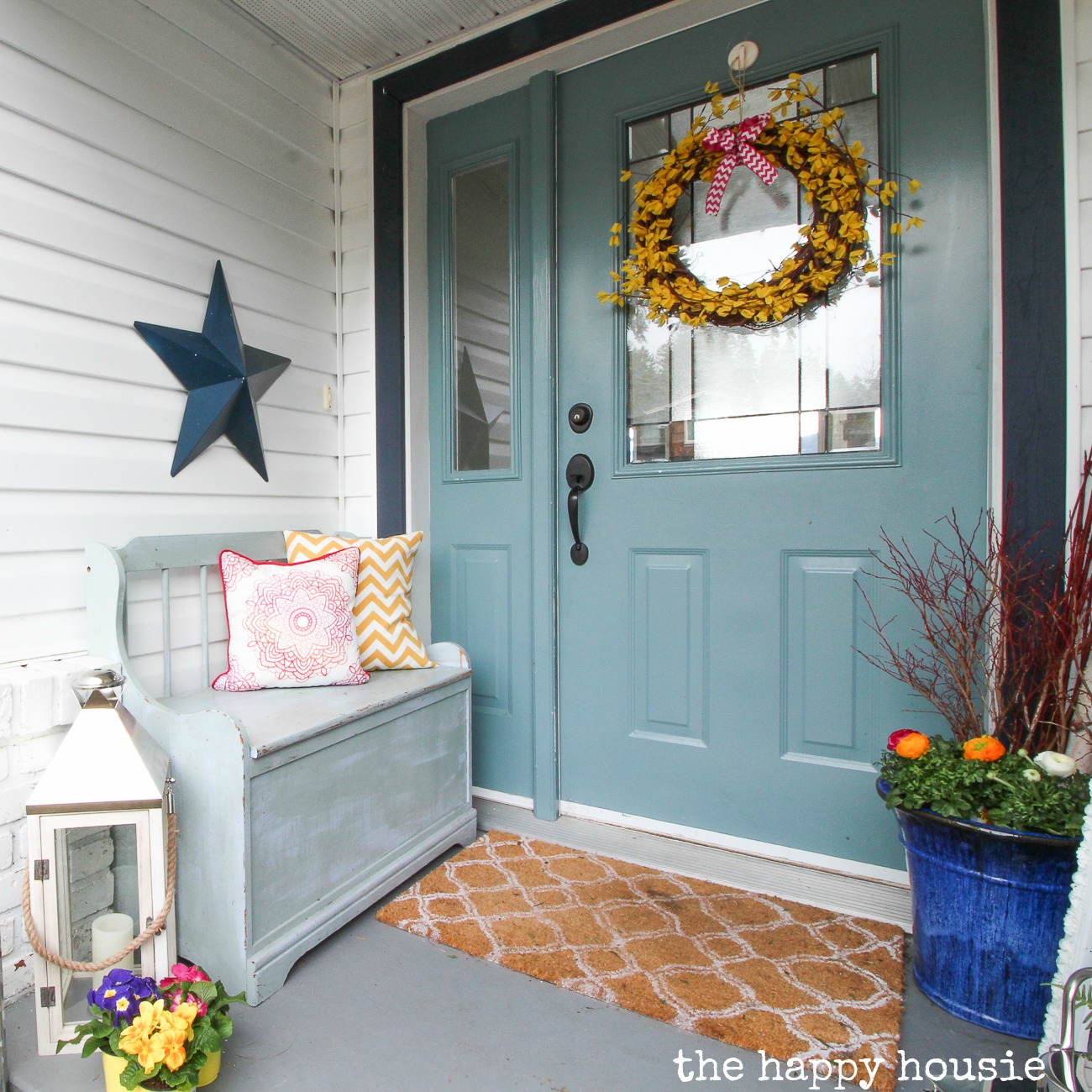 A porch decorated for spring with a wreath on the door.