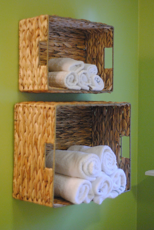 Baskets hanging on the wall with rolled up towels in them.