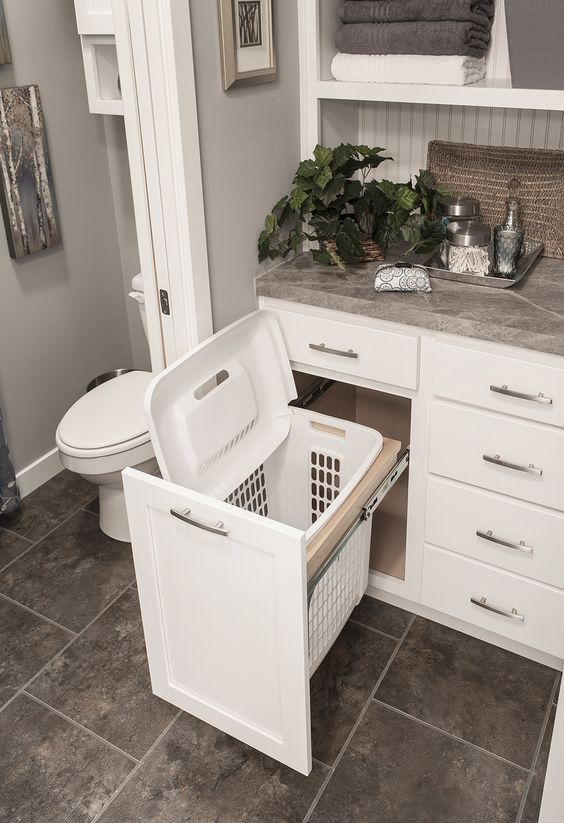 A built in clothes hamper in the bathroom under the sink.