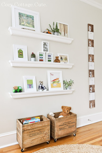 Floating shelves with pictures on them and wooden rolling toy boxes underneath.
