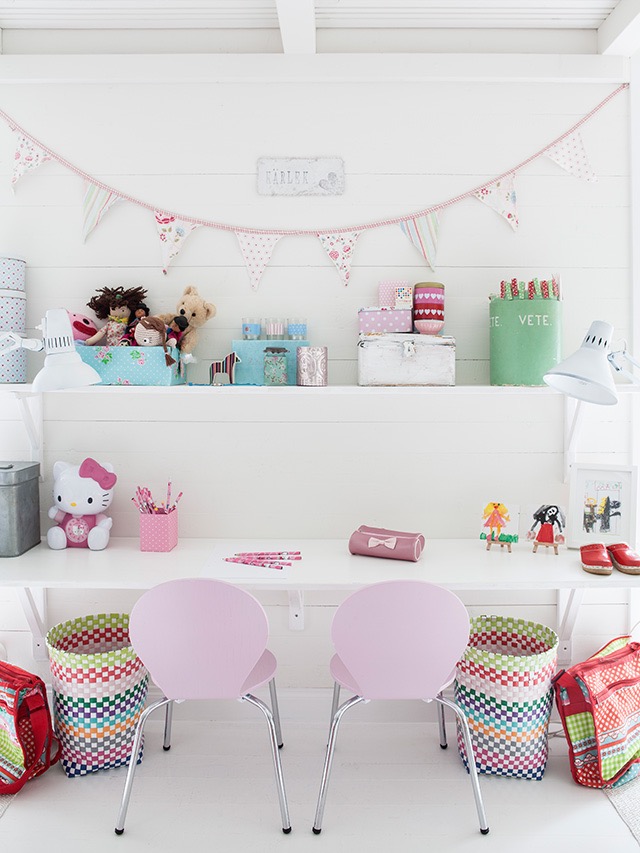 Small pink chairs are at a white desk.