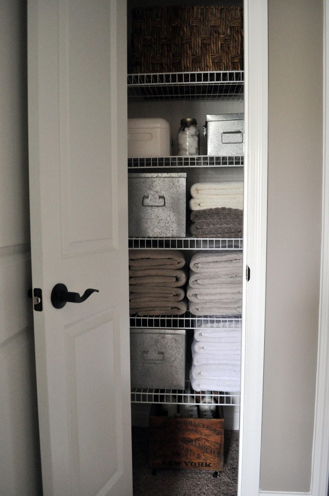 A narrow linen closet with folded towels.