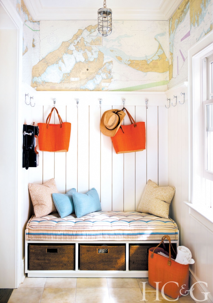 A bend in the entryway with pillows and a map above it on the wall.