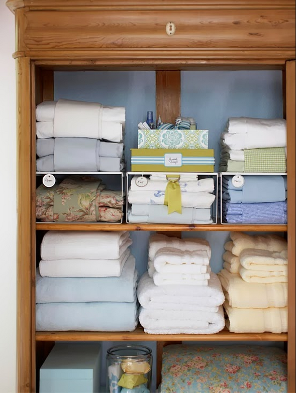 A wooden shelf with a fully organized linens inside.