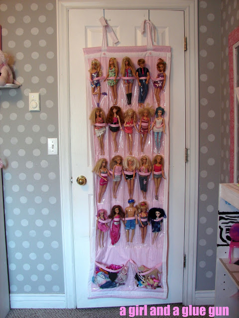 Barbies hanging in a hanging shoe shelf on the back of the door.
