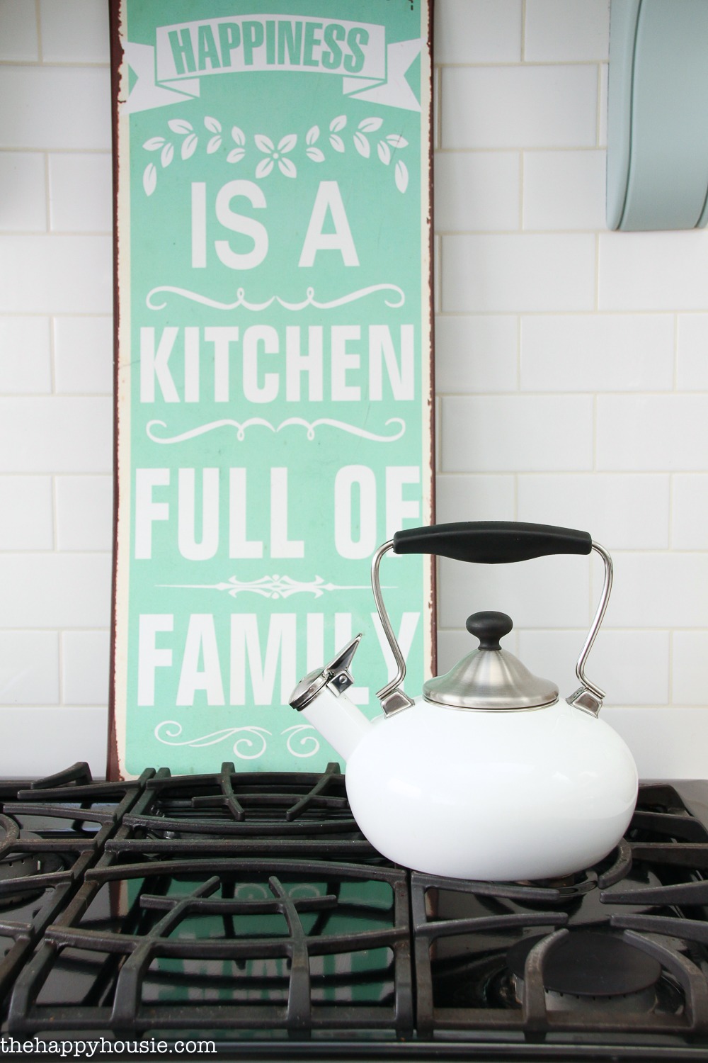 A white kettle is on the stove.