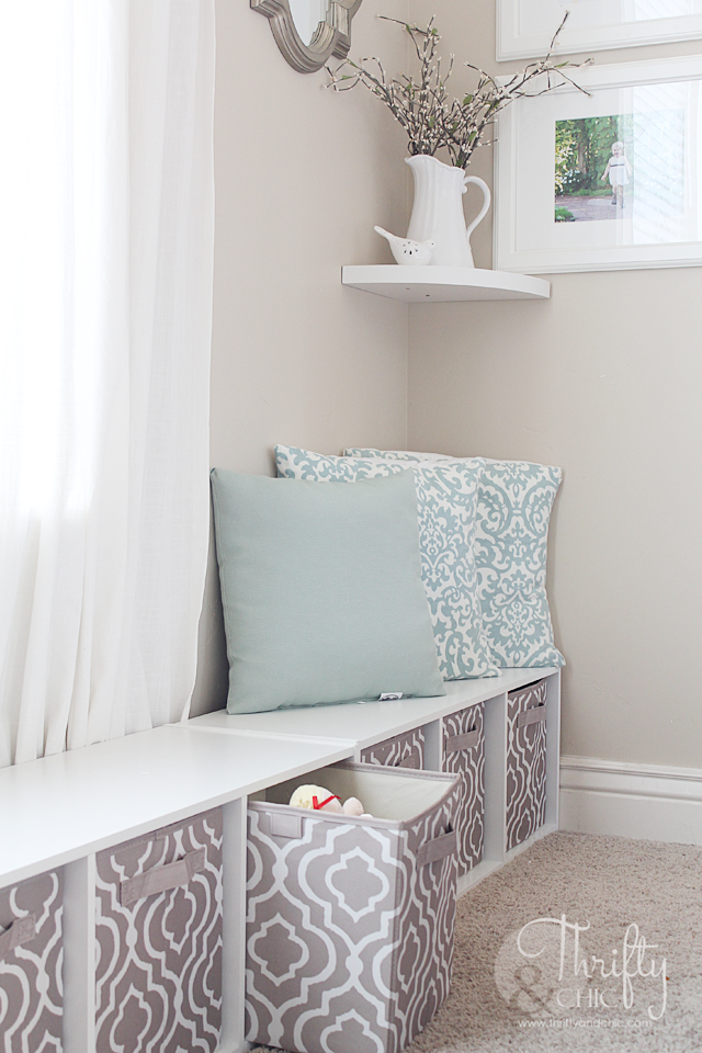 A sitting bench with throw pillows and baskets underneath it for storage.