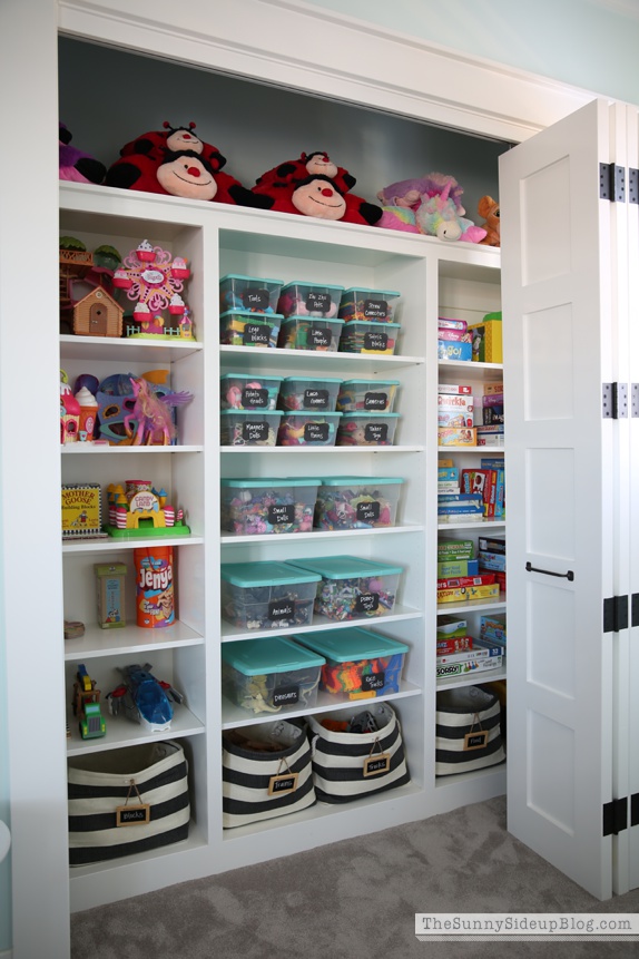 A large closet with shelves filled with toys organized.