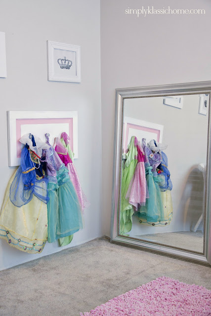 Coat hooks on the wall with dress up clothes hanging on it.