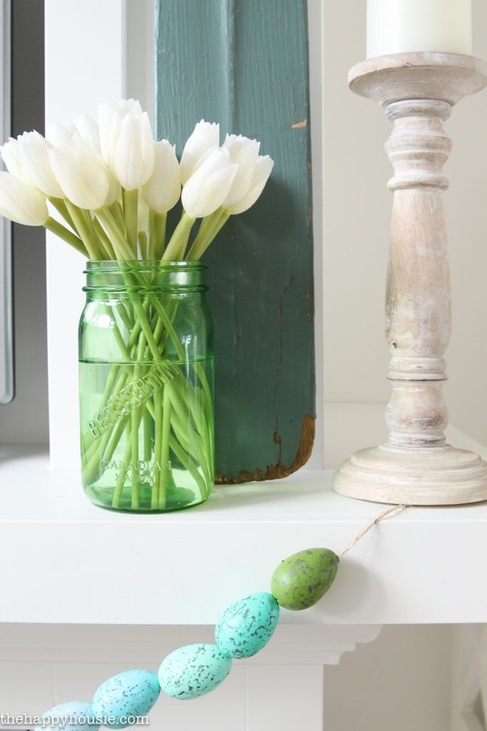 White tulips in a glass jar on the mantel.
