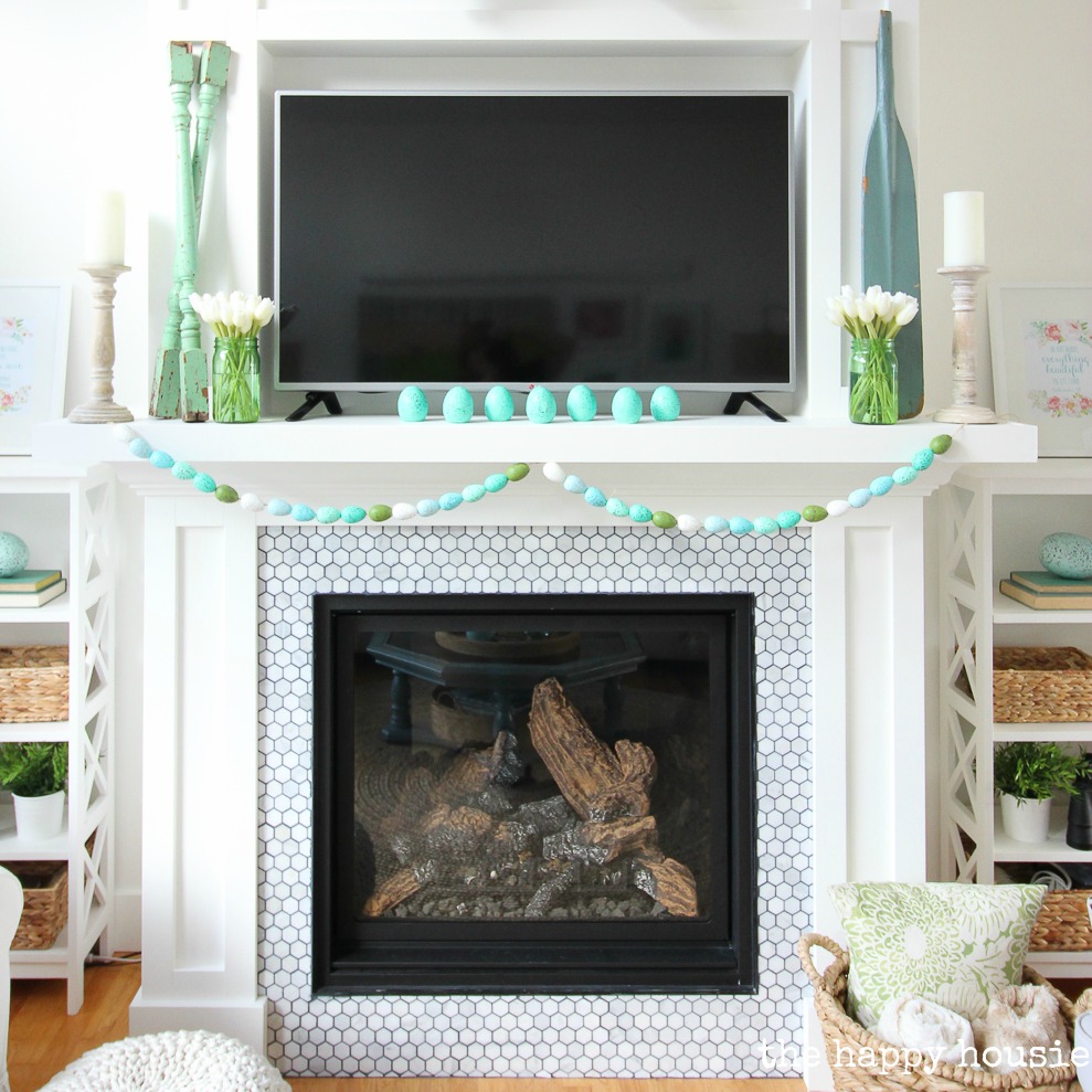 A white fireplace with pops of turquoise.