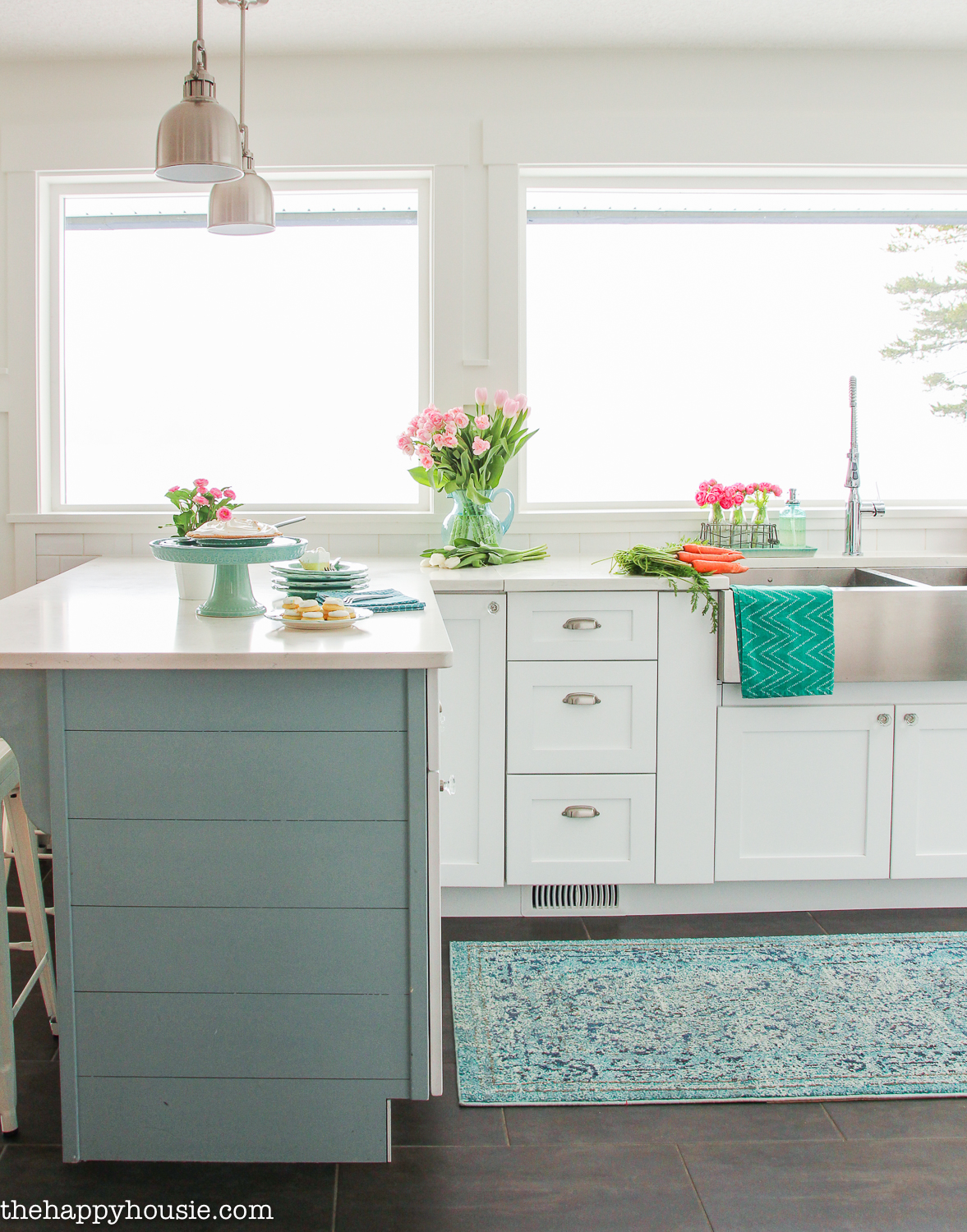 White kitchen cabinets with a soft blue island and spring flowers on the counters.