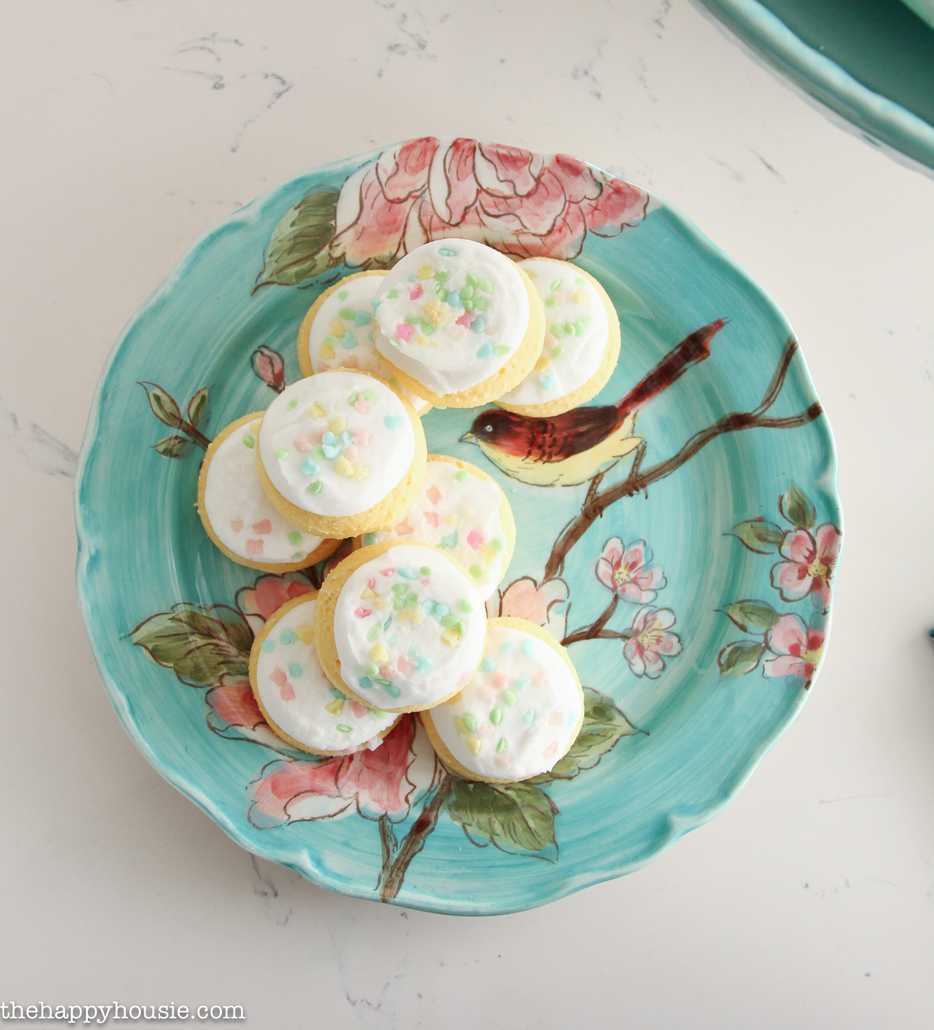 A blue, pink and floral/bird patterned plate with cookies on it.