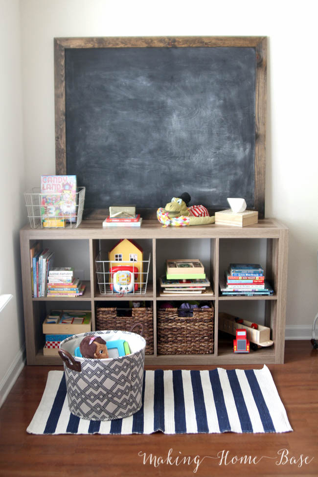 Shelves with a chalkboard and a small rug in front of it.