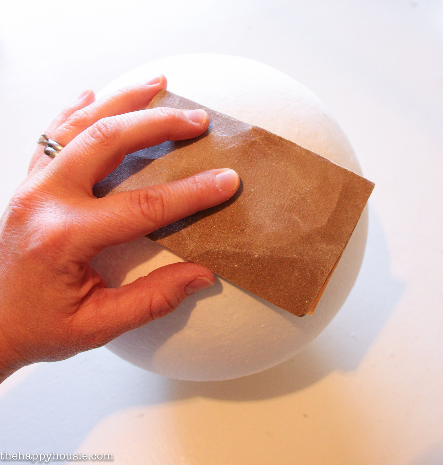Using sandpaper to smooth the sphere.