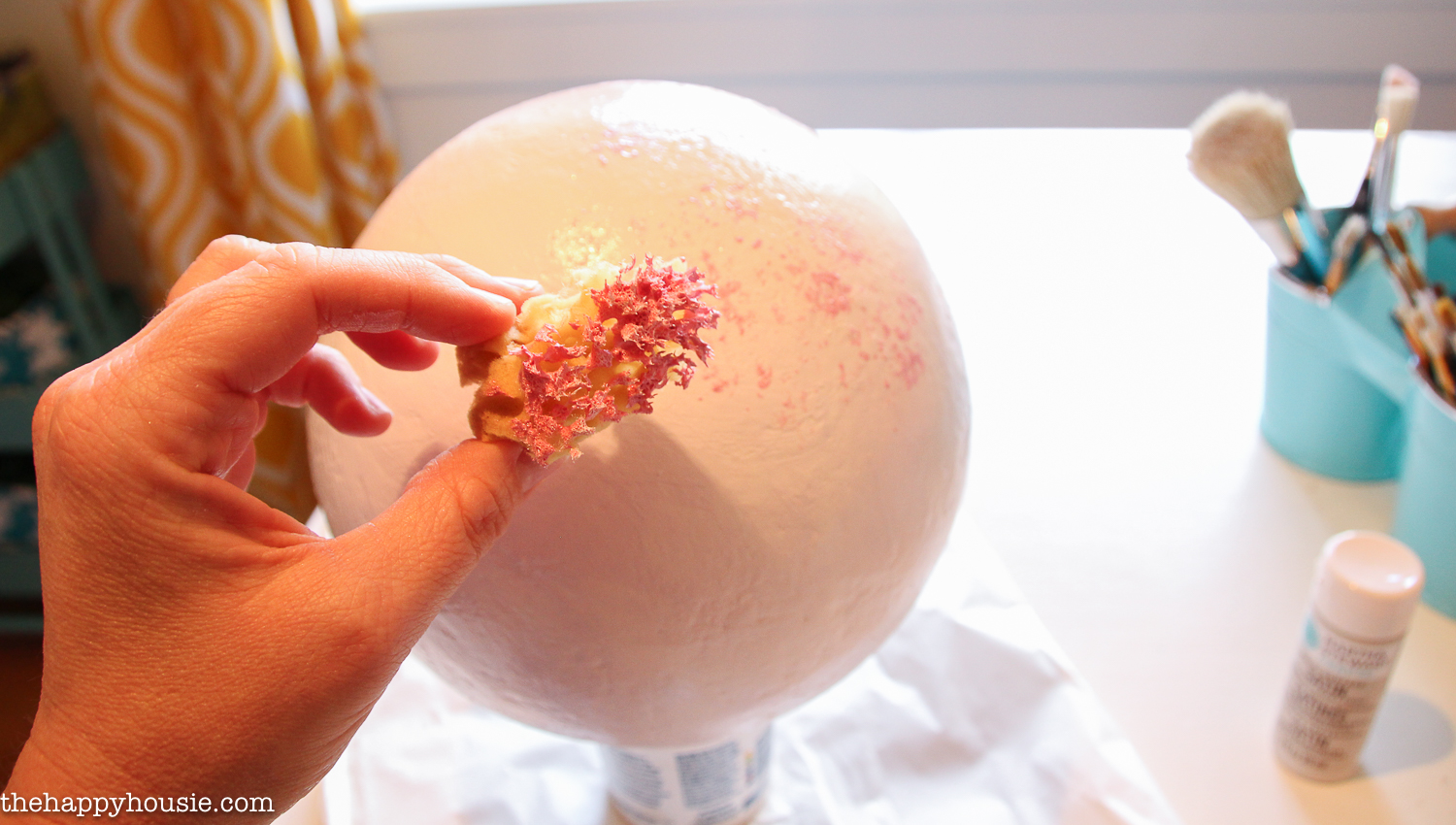 Using a sea sponge to speckle pink on the sphere.
