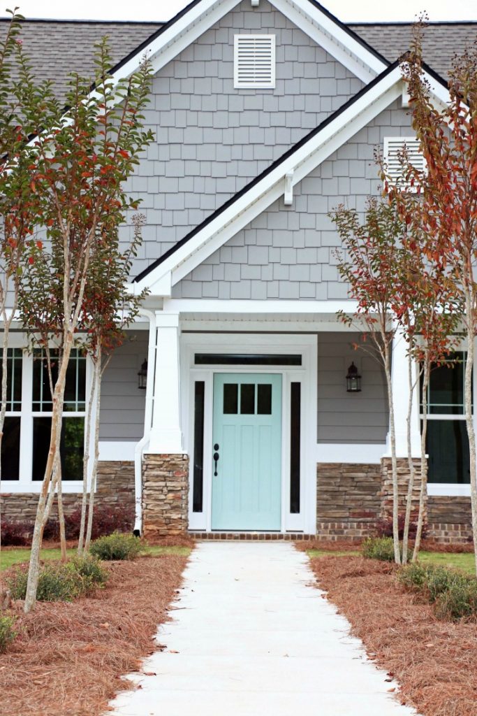 A gray house with an aqua coloured door.