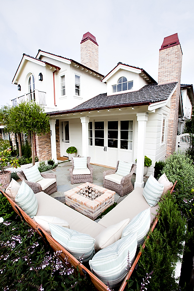 A White House, with white sectional outdoor sofa around the fire pit.