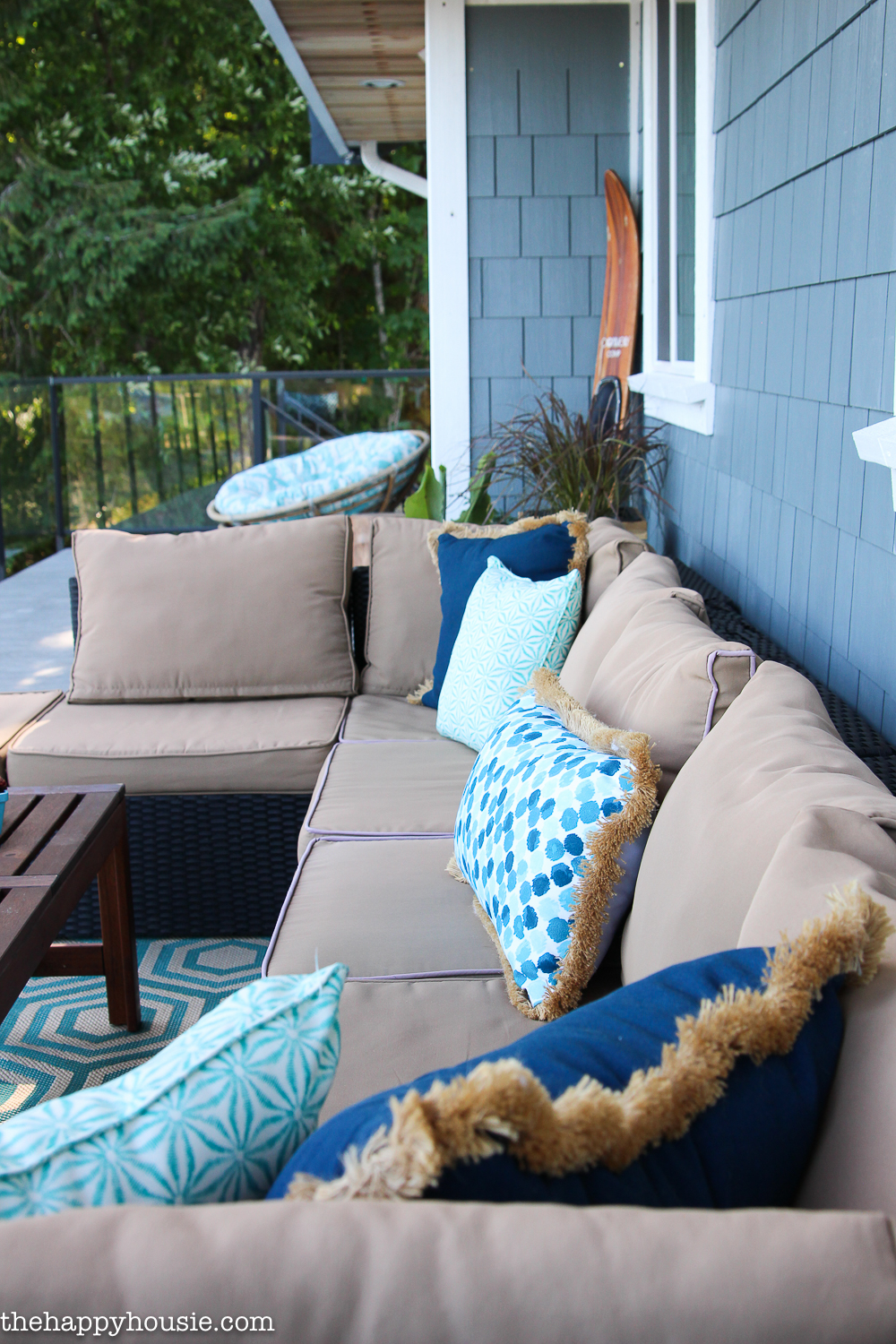 There is an outdoor patio with blue throw pillows on it.