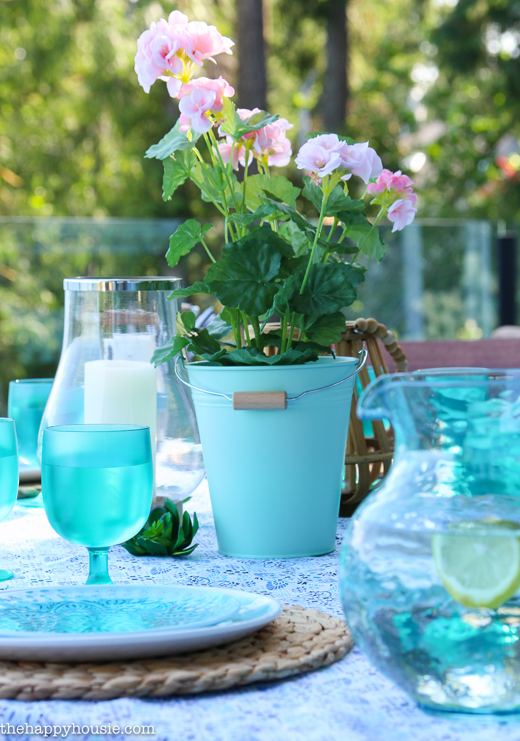 A light blue bucket planter with the light pink flowers.