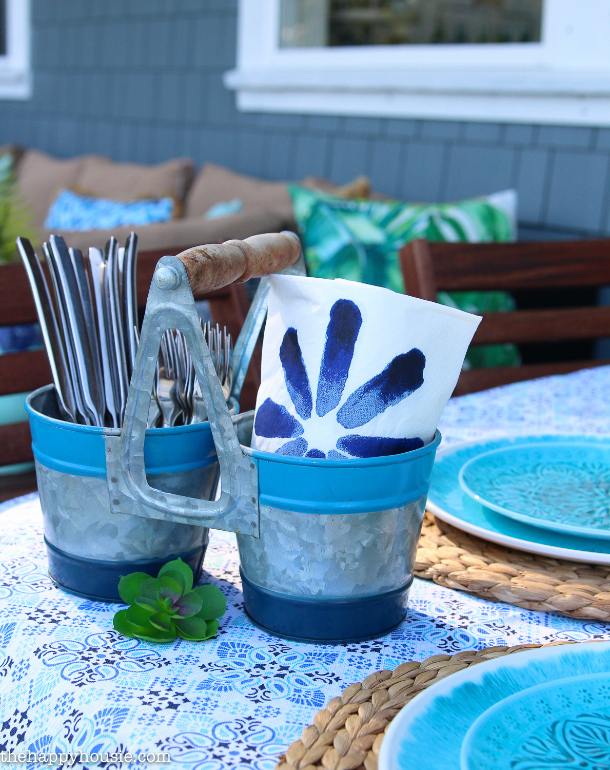There is galvanized containers on the table that have cutlery in them.
