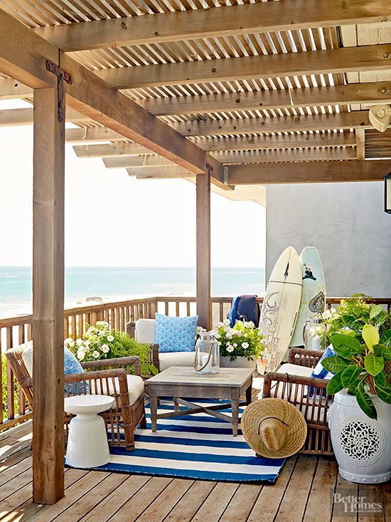 A blue and white striped rug outdoors on the wooden patio overlooking the water.