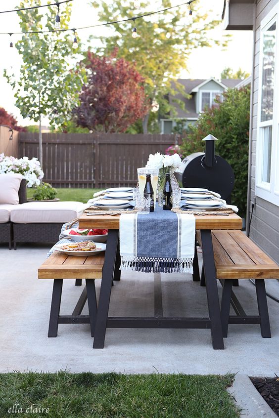A wooden picnic table all set for dinner outside.