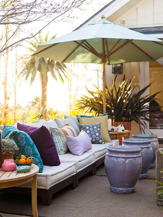 Bright coloured pillows on the outdoor couch with a small shade umbrella.