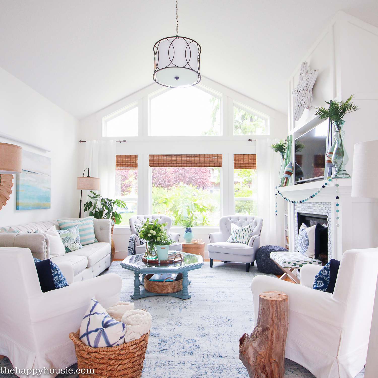 A white beachy living room with white couches, wood details and wicker baskets.