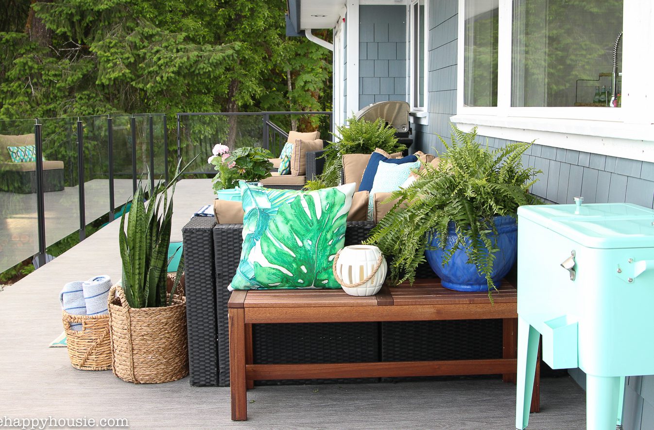 There is an outdoor sofa with plants surrounding it on the deck.
