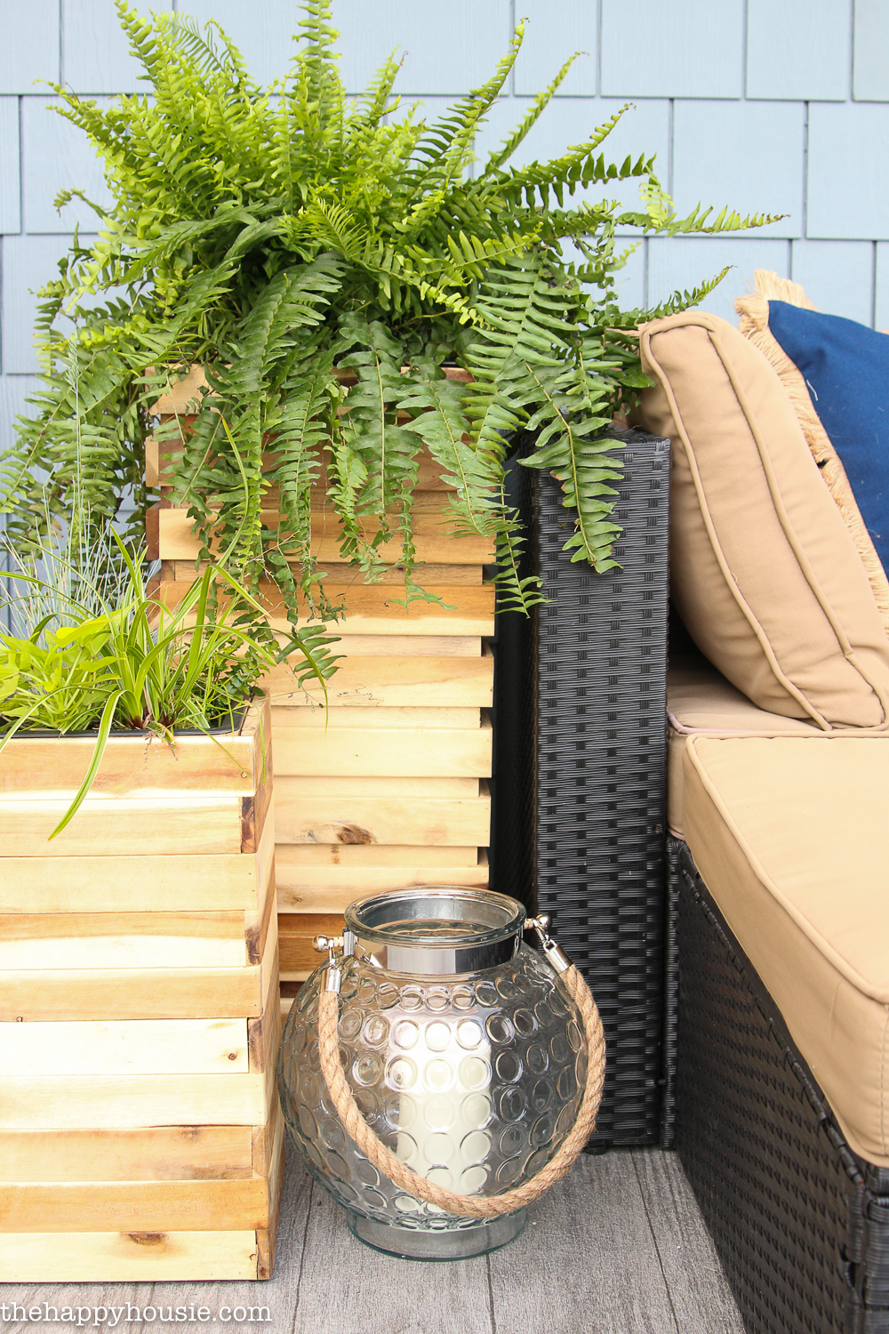 A large wooden planter beside the couch with a fern in it.