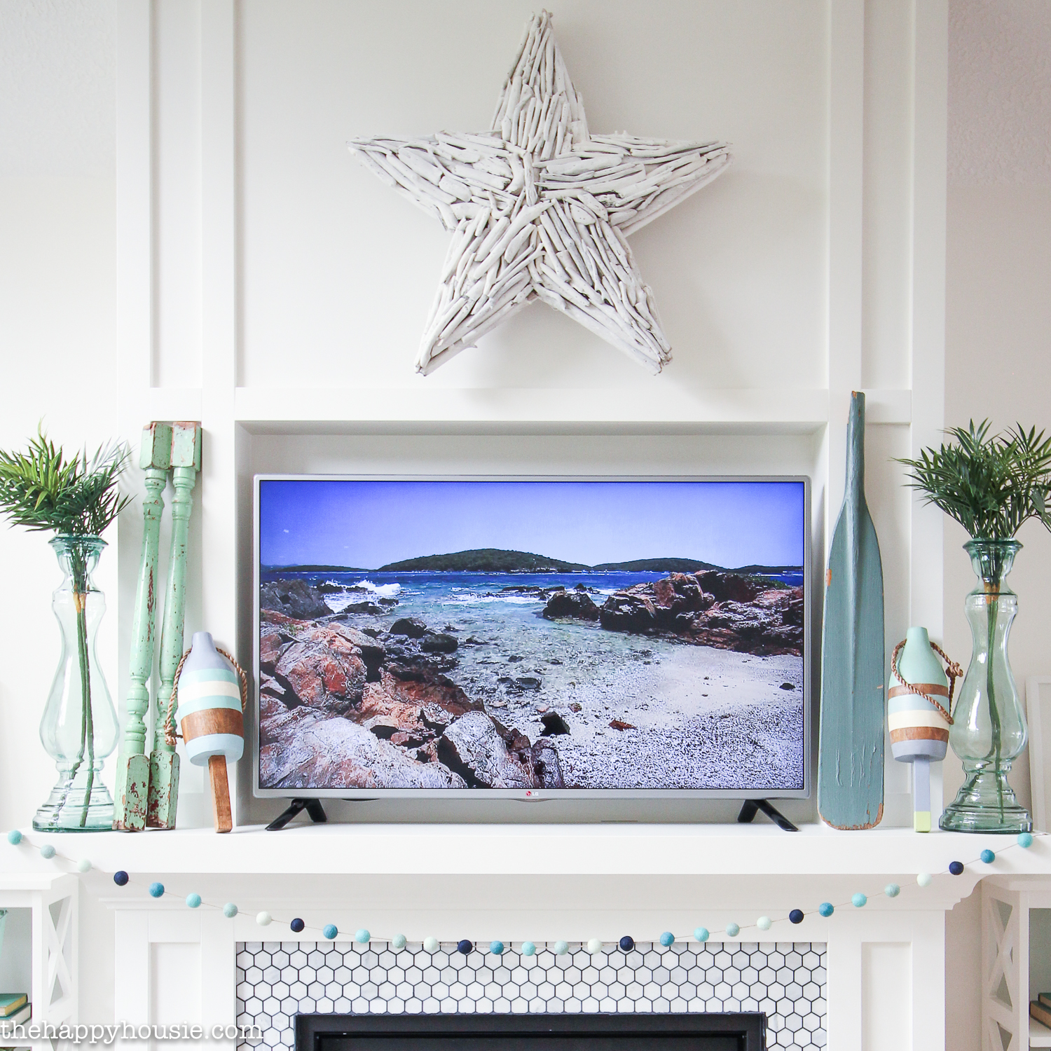A white fireplace mantel with beachy decor on it.