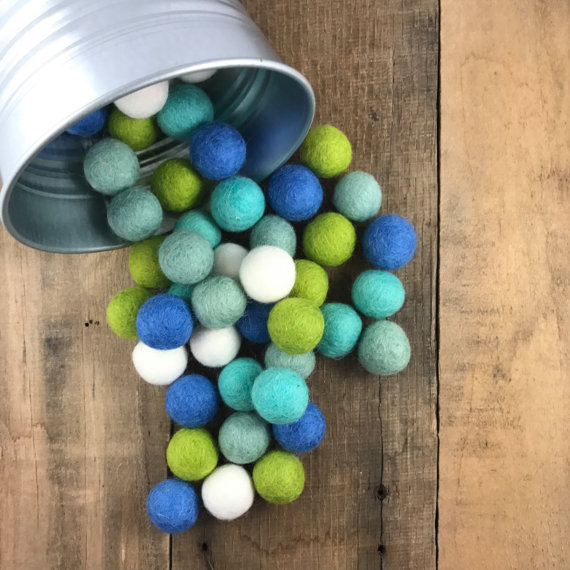 A container lying on its side with blue, green, white felt balls spilling out.