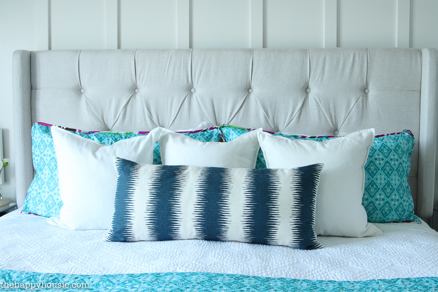 A comfy bed with throw pillows in blue and white.
