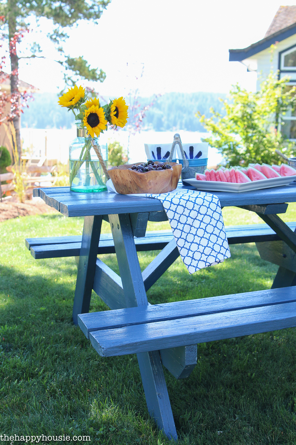 A picnic table with watermelon slices and a sunflower on it.