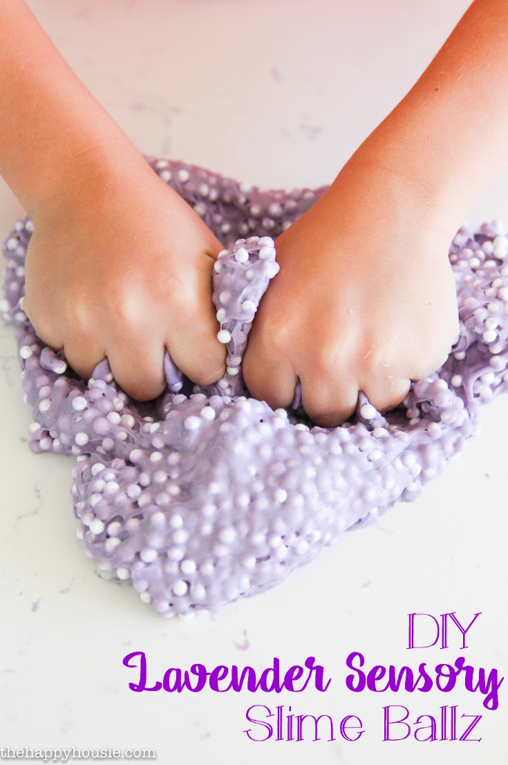 A child's hands kneading lavender slime.