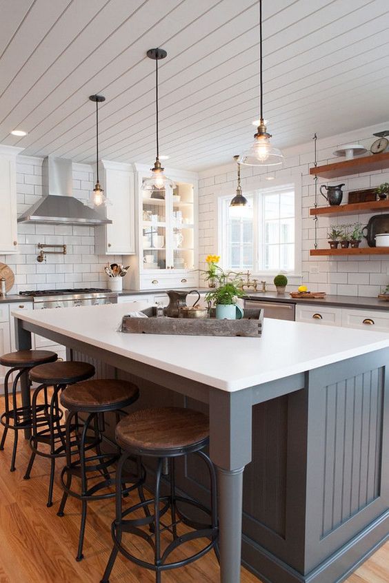 A planked wall in the kitchen with stools underneath the kitchen island.