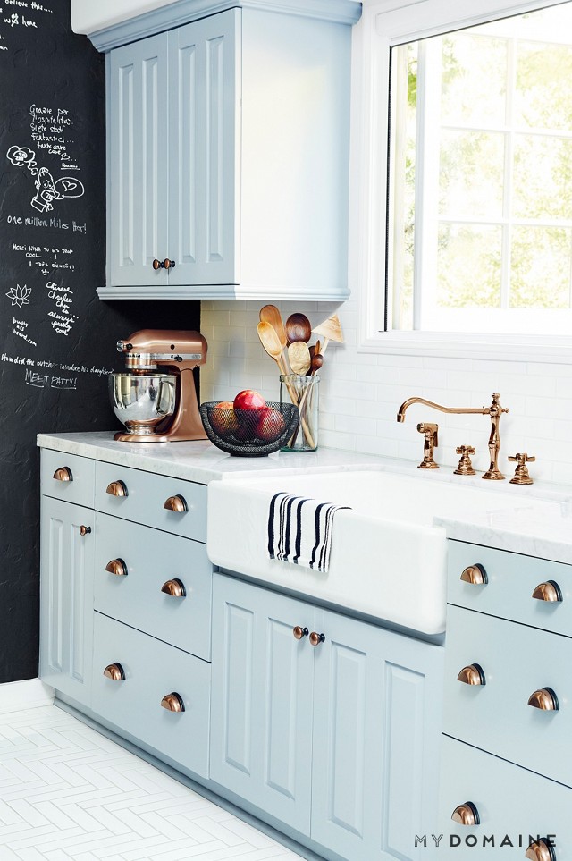 A light baby blue kitchen with brass hardware.