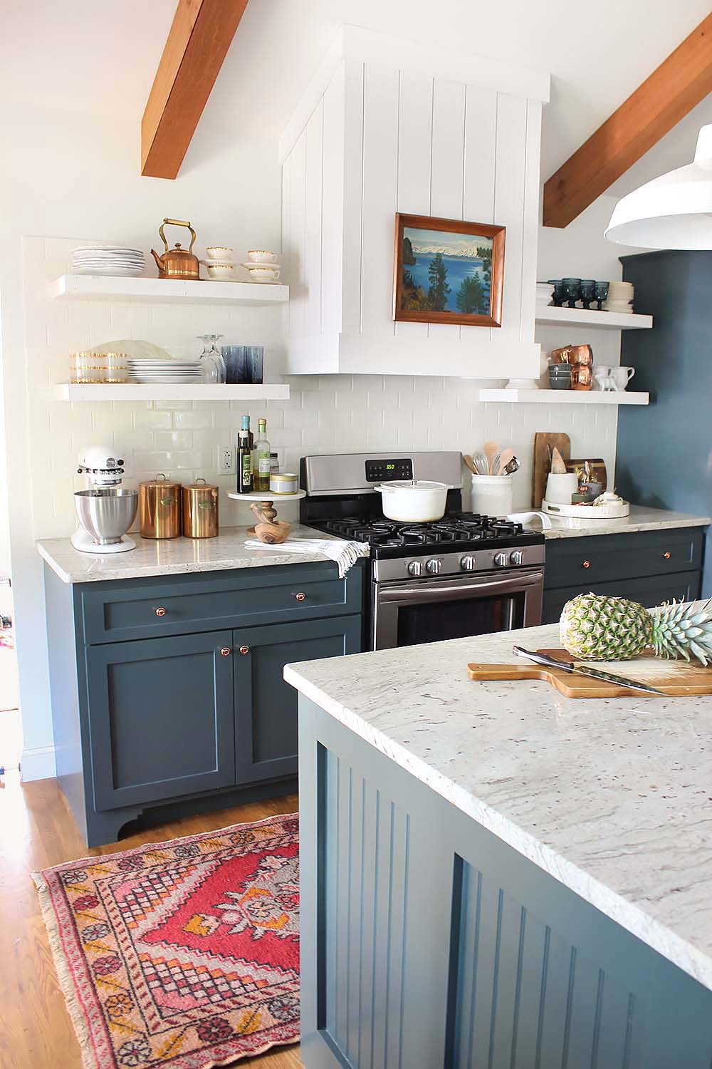A blue - gray cabinets with wooden beams in farmhouse kitchen.