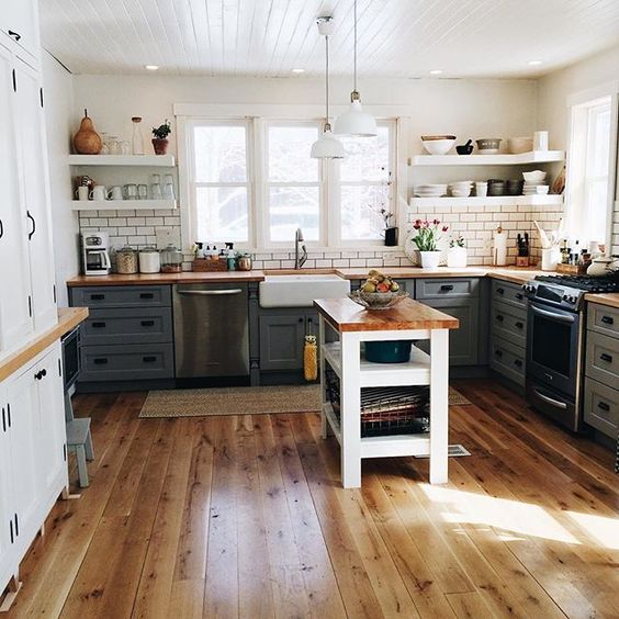 A wooden floor, and dark gray cabinets with a white backsplash and open white shelves.