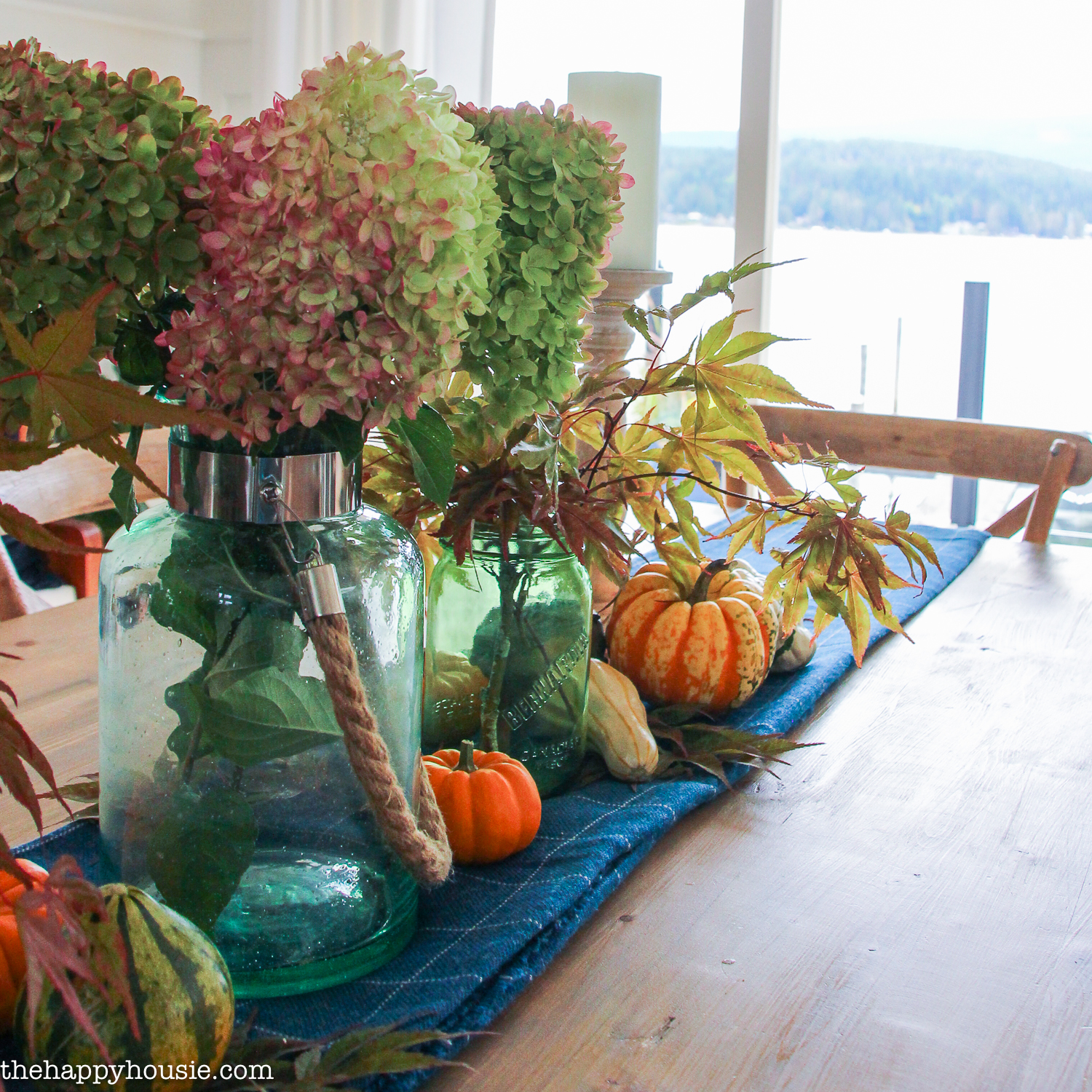A blue table runner with pumpkins and hydrangeas on it.