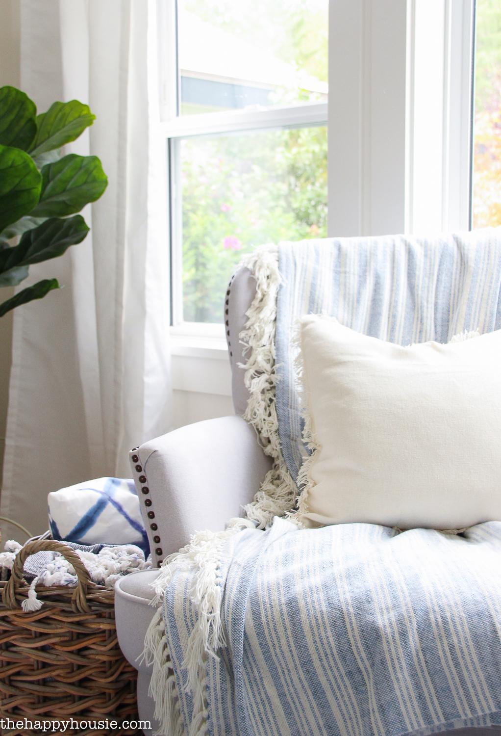 A cotton blue and white throw blanket is on an armchair.