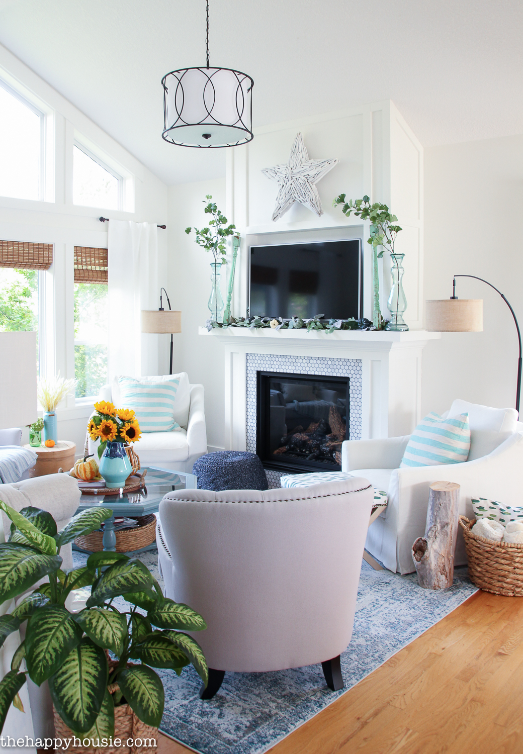 A white fireplace mantel with an area rug and plants in the corner.