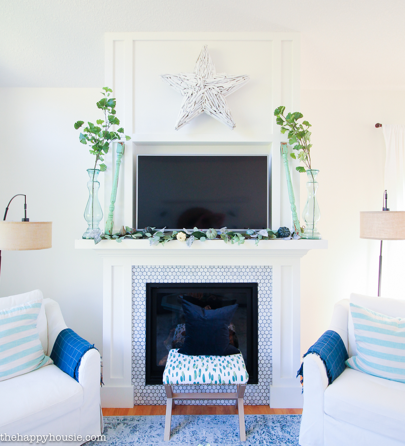 A fireplace with a TV on the mantel and a small stool in front of it with a blue pillow on the stool.