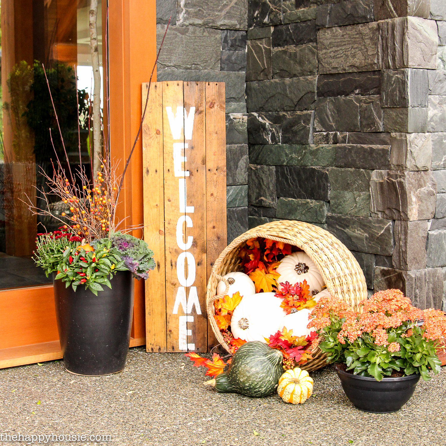 Floral planters and a basket filled with fall decor on the porch.