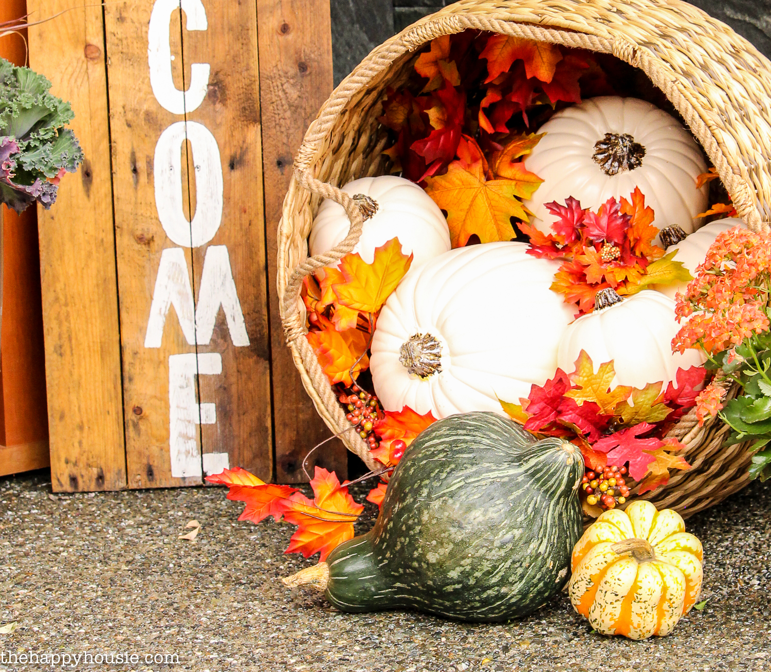 A small basket filled with fall leaves, pumpkins and gourds.