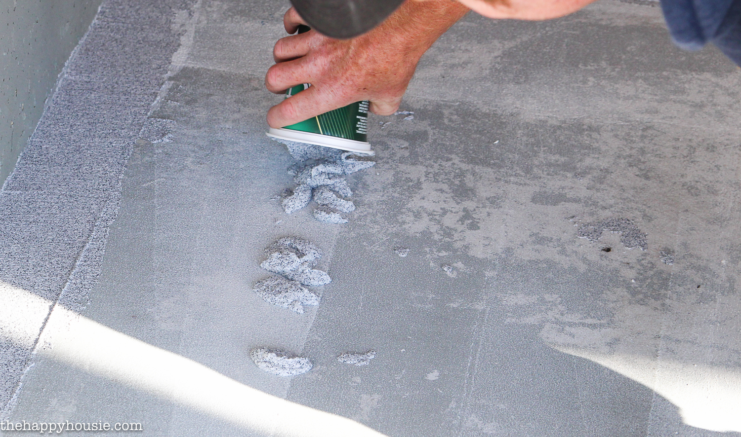Applying more of the product to the concrete patio floor.