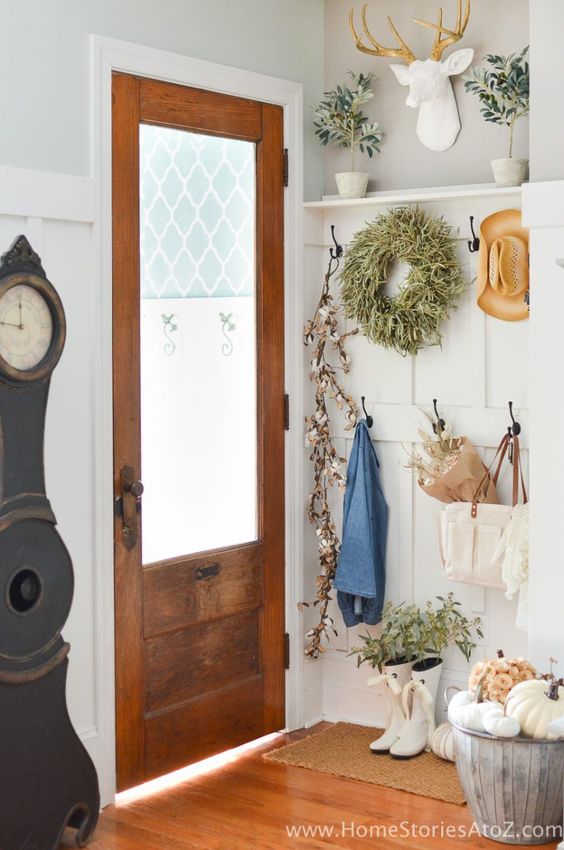White boots and a wreath are beside a wooden door.