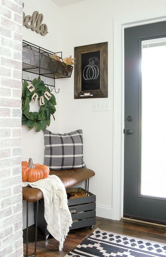 A small bench with a pumpkin on it and a small rug in front of the door.